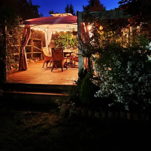 Taras pod altaną wieczorem, oświetlony girlandą lampek
