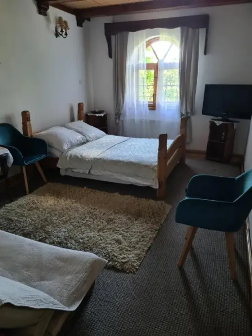 Pokój z łóżkiem, fotelami i łukowym oknem